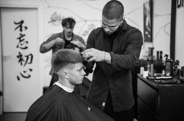Barber przy pracy, w tle kaligrafia 初心