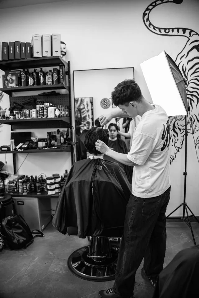 Barber przy pracy na tle muralu z tygrysem